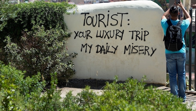 "Dein Luxustrip ist mein tägliches Elend" - Schriftzug auf einer Wand in Barcelona (Bild: AFP)