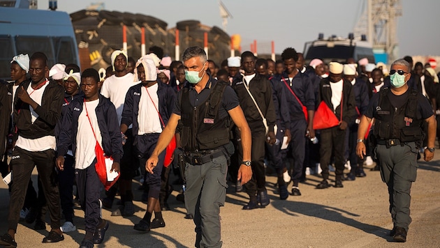In Sizilien ankommende Flüchtlinge werden zunächst zur medizinischen Untersuchung eskortiert. (Bild: AP)