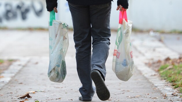 Ein Mann trägt seine Einkäufe in zwei Plastiktragetaschen heim. Ein alltägliches Bild. (Bild: APA/HELMUT FOHRINGER)