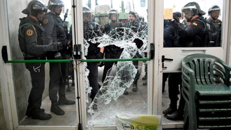 Polizeieinheiten brechen die Tür zu einem Wahllokal auf. (Bild: APA/AFP/LLUIS GENE)