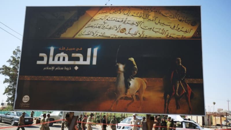 Dieses Plakat in Hawidscha erinnert noch an den Dschihad-Aufruf des IS. (Bild: APA/AFP/AHMAD AL-RUBAYE)