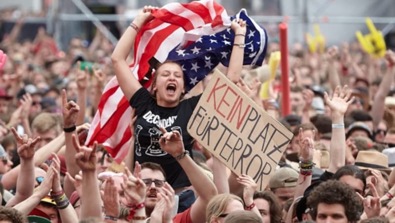 Zuschauer halten beim Konzert ein "Kein Platz für Terror"-Schild hoch. (Bild: APA/dpa/Thomas Frey)