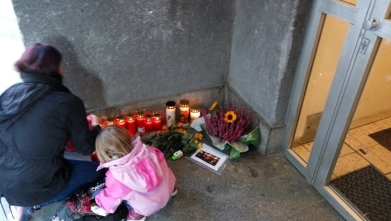 Blumen und Kerzen vor dem Wohnhaus der Opfer in Wien (Bild: APA/ANDREAS WESTPHAL)