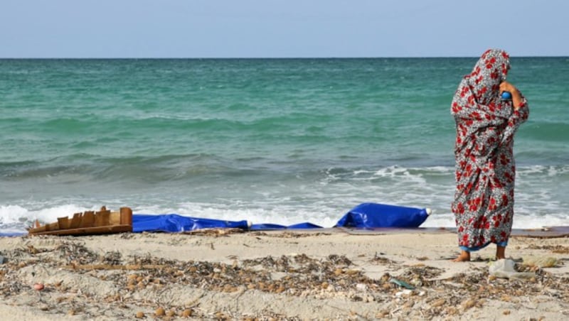 Eine Libyerin begutachtet die Reste eines in Küstennähe gekenterten Schlauchboots (Archivbild). (Bild: APA/AFP/STRINGER)