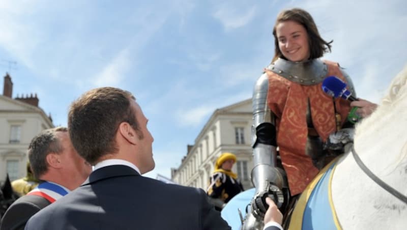 Der damalige Wirtschaftsminister Emmanuel Macron schüttelt im Jahr 2016 der Darstellerin der Johanna von Orleans die Hand. (Bild: AFP)