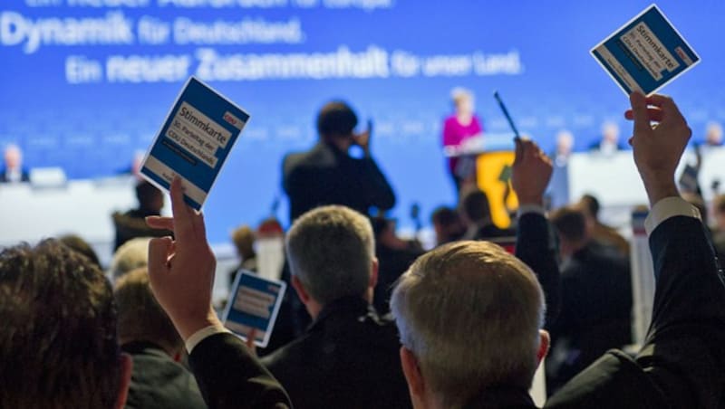 CDU-Mitglieder halten ihre Stimmkarten hoch. (Bild: AFP)