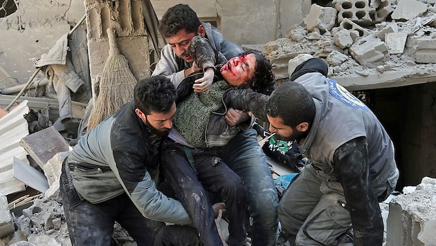 Helfer bergen ein verletztes Kind nach einem Bombardement in der Stadt Hamouria in der Region Ost-Ghouta. (Bild: AFP)