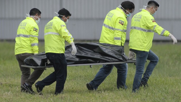 Ecuadorianische Einsatzkräfte beim Abtransport der Leiche eines blinden Passagiers (Bild: AP)