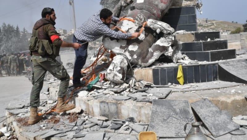 Syrische Rebellen entfernen das Seil, mit dem sie die kurdische Statue gestürzt haben. (Bild: AFP )