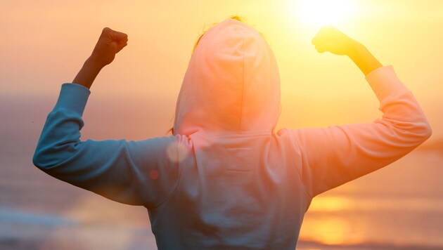 Back view of strong motivated woman celebrating workout goals towards the sun. Morning healthy training success. (Bild: Dirima/stock.adobe.com)