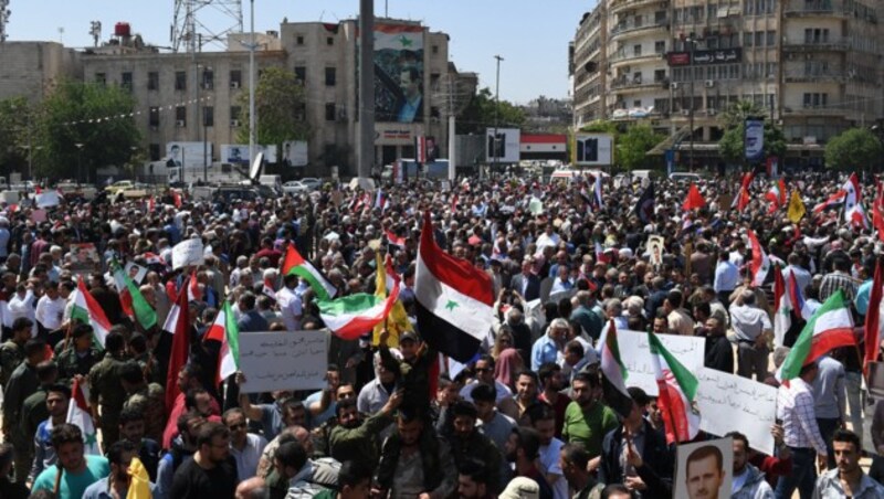 Syrer gehen nach den Luftschlägen für ihren Präsidenten auf die Straßen, schwenken syrische Flaggen. (Bild: AFP)