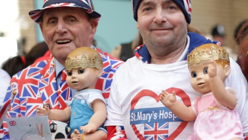 Die Royal-Fans Terry Hutt (l) und John Loughrey (r) feiern vor Kates Krankenhaus die Geburt des kleinen Prinzen. (Bild: AFP or licensors)