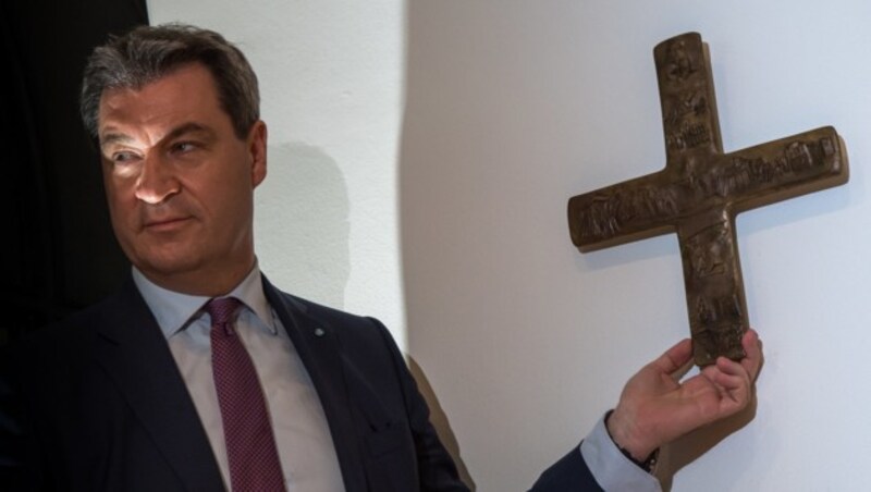 Der bayrische Ministerpräsident Markus Söder (CSU) hängt ein Kreuz im Eingangsbereich der Staatskanzlei auf. (Bild: APA/dpa/Peter Kneffel)