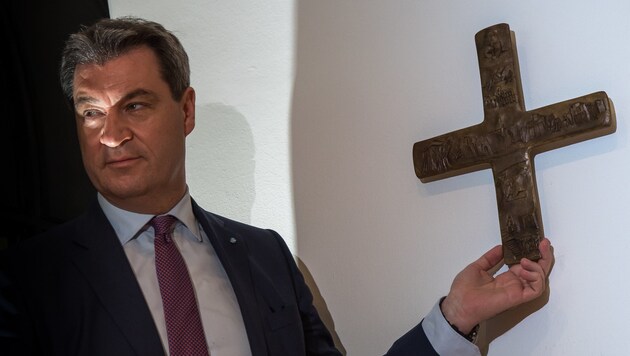 Der bayrische Ministerpräsident Markus Söder (CSU) hängt ein Kreuz im Eingangsbereich der Staatskanzlei auf. (Bild: APA/dpa/Peter Kneffel)