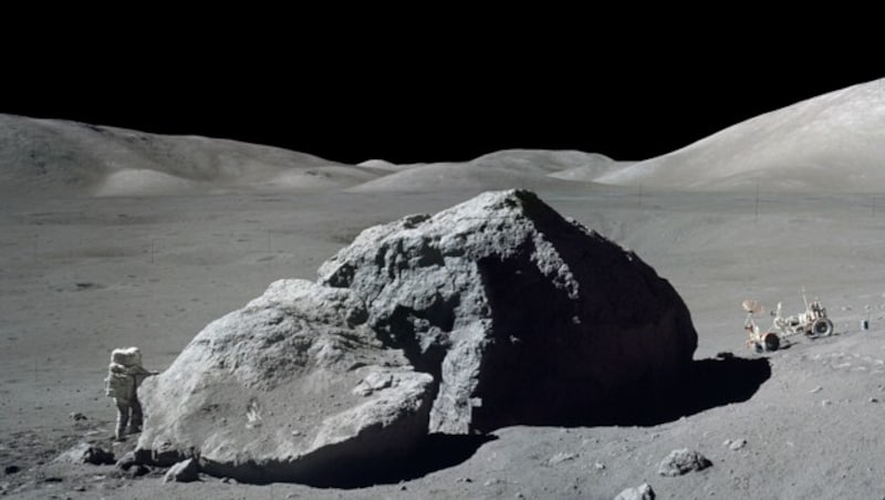 Harrison Schmitt bei einem Mond-Spaziergang, im Hintergrund rechts das Mondmobil (Bild: NASA/Eugene Cernan)