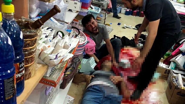 Ein Verletzter liegt nach den Schüssen in Suruc am Boden eines Geschäfts. (Bild: APA/AFP/Mezopotamya News agency)