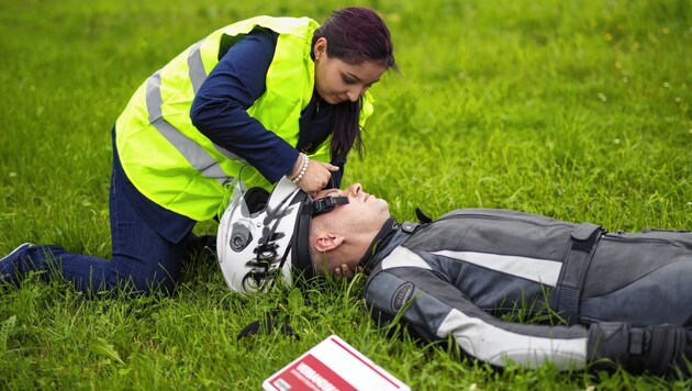Eine Helferin mit Warnweste nimmt vorsichtig den Helm eines verunglückten Bikers ab (gestelltes Bild). (Bild: Österreichisches Rotes Kreuz (ÖRK)/Thomas Holly Kellner)