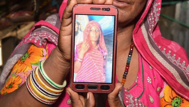 Eine trauernde Verwandte zeigt ein Foto der getöteten Shantadevi Nath. Die Frau war wegen WhatsApp-Gerüchten für eine Kindesentführerin gehalten worden und einem wütenden Mob zum Opfer gefallen. (Bild: APA/AFP/SAM PANTHAKY)