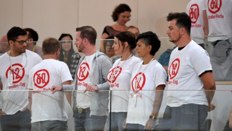 Menschen auf den Zuseherrängen mit T-Shirts gegen den „12-Stunden-Tag“ im Rahmen einer Sondersitzung des Nationalrates (Bild: APA/ROLAND SCHLAGER)