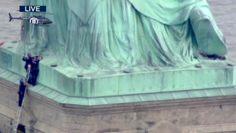 Die Demonstrantin (im Bild rechts liegend) beschäftigte die Polizei und legte das Wahrzeichen lahm. (Bild: AP)