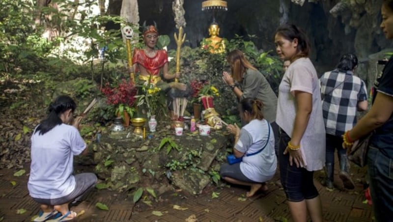 Familienmitglieder der eingeschlossenen Fußballmannschaft beten vor einem Schrein. (Bild: AFP)