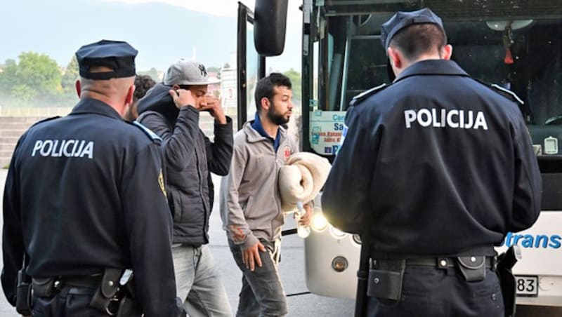 Bosnische Polizisten kontrollieren in der Grenzstadt Bihac per Bus angereiste Migranten aus Asien. (Bild: APA/AFP/ELVIS BARUKCIC)