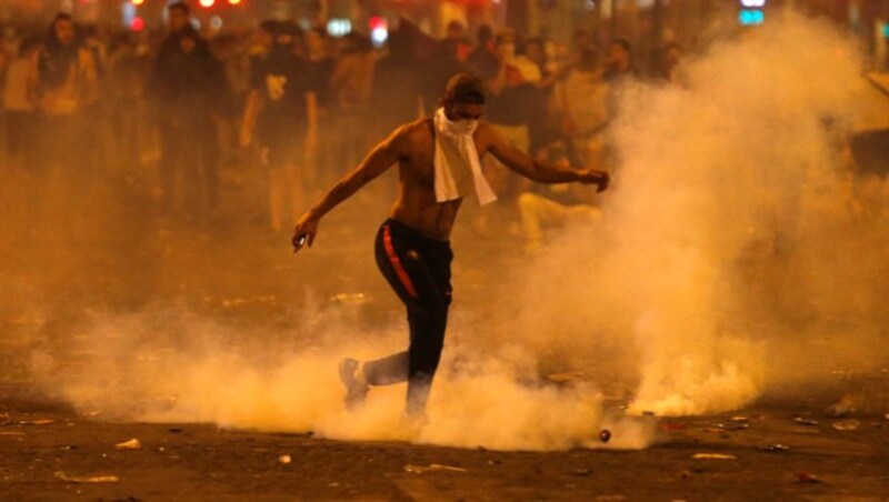 Ein Mann tritt auf den Champs-Elysees eine Tränengas-Dose weg. (Bild: AP)