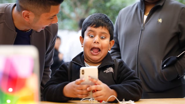 Ein Bub schneidet Grimassen, um das animierte Emoji-Feature des iPhone X auszuprobieren. (Bild: APA/AFP/Elijah Nouvelage)