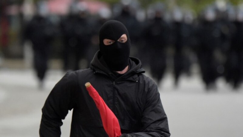 Ein vermummter Teilnehmer der rechten Demo (Bild: AP)