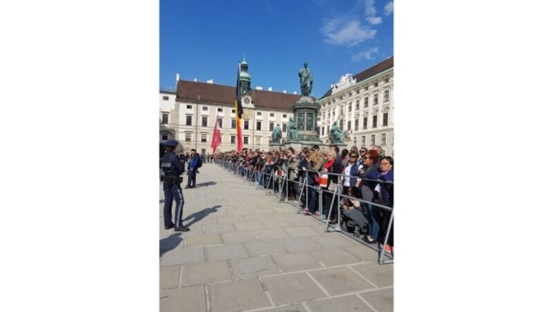 Hinter Absperrungen drängen sich Royal-Fans, um vor der Hofburg einen Blick auf König Philippe und Königin Mathilde beim militärischen Empfang durch Bundespräsident Van der Bellen zu erhaschen. (Bild: krone.tv)