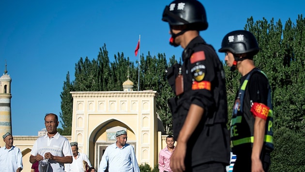 Chinesische Polizisten überwachen Uiguren nach dem Gebet in einer Moschee in der Unruheprovinz Xinjiang. (Bild: AFP)