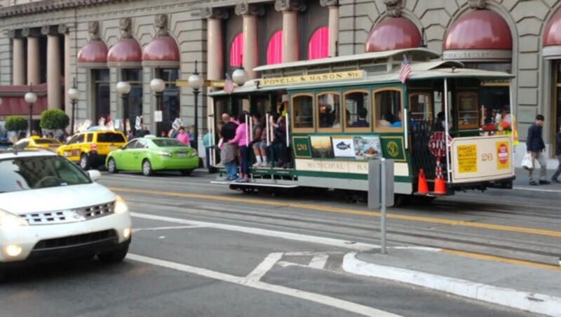 Ein ikonisches Cablecar vor einem Luxushotel im Zentrum von San Francisco. Vor dem Hoteleingang wird demonstriert. (Bild: Dominik Erlinger)