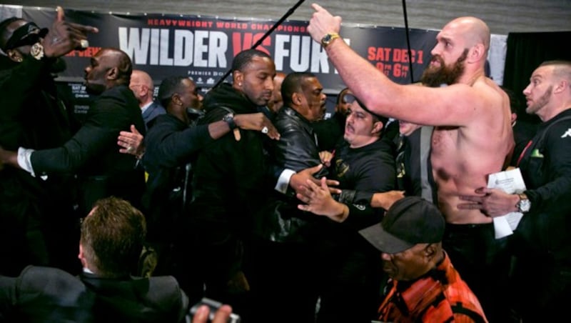 Boxers Deontay Wilder, far top left, and Tyson Fury, second from right, are separated by their respective team members after exchanging words at a news conference in Los Angeles, Wednesday, Nov. 28, 2018, ahead of their heavyweight world championship boxing match at Staples Center, on Dec. 1. (AP Photo/Damian Dovarganes) (Bild: AP)