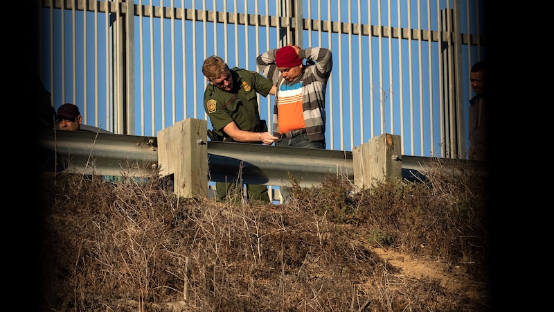 Migranten ergeben sich nach dem Überwinden des Zauns den Grenzschützern und suchen um Asyl in den USA an. (Bild: AFP)