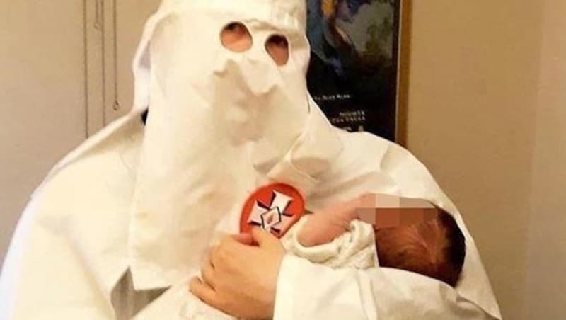 Adam Thomas trägt eine Ku-Klux-Klan-Robe und seinen neugeborenen Sohn auf dem Arm. (Bild: West Midlands Police)