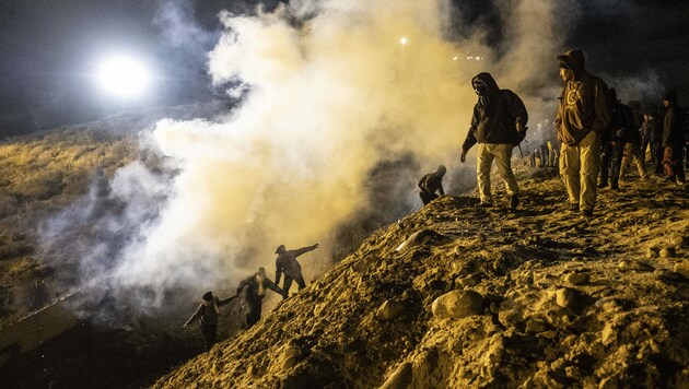 Migranten laufen vor den Nebelwolken aus Tränengas davon. (Bild: AFP )