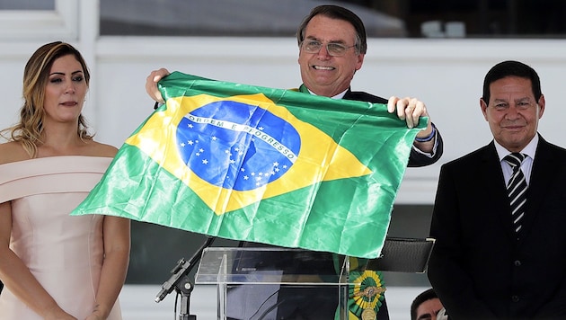 Ex-Militär Jair Bolsonaro schwenkt nach seiner Amtseinführung in Brasilia neben seiner Frau Michelle und seinem Vizepräsidenten, Ex-Militär Hamilton Mourao, die brasilianische Flagge. (Bild: AP)