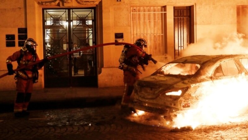 Feuerwehrmänner löschen am 5. Jänner in Paris ein bei den „Gelbwesten“Protesten in Brand gestecktes Auto. (Bild: AFP)