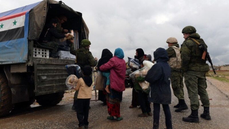 Russische und syrische Soldaten helfen Menschen, die sich aus den Kriegsgebieten befreien konnten, bereits mit humanitären Gütern. (Bild: APA/AFP/George OURFALIAN)