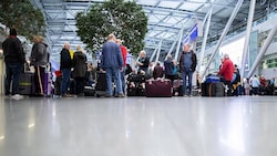 Reisende warten mit ihrem Gepäck am Flughafen Düsseldorf. (Bild: APA/dpa/Marcel Kusch)