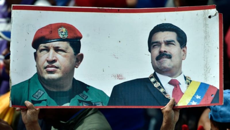 Ein Maduro-Unterstützer hält ein Plakat in die Höhe, das diesen (re.) und seinen verstorbenen Vorgänger Hugo Chavez zeigt. (Bild: APA/AFP/LUIS ROBAYO)