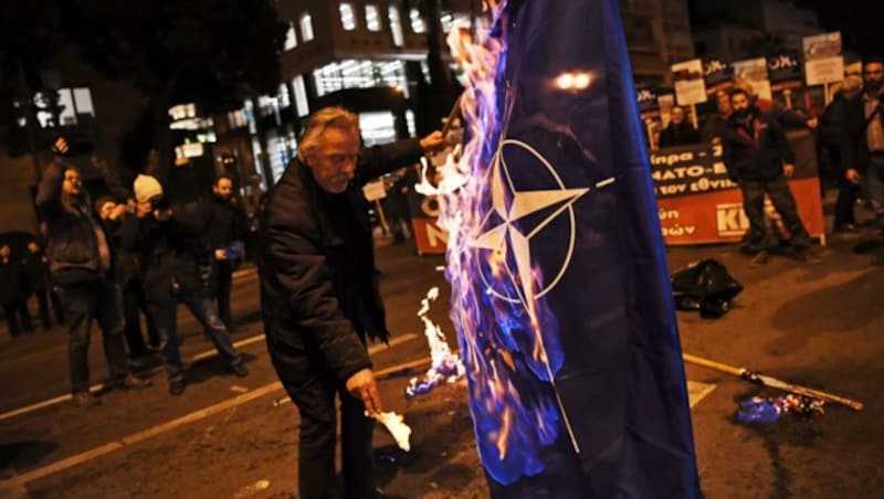 Ein griechischer Kommunist demonstriert, was er von der Namensänderung Mazedoniens hält, und zündet eine NATO-Flagge an. (Bild: AP)