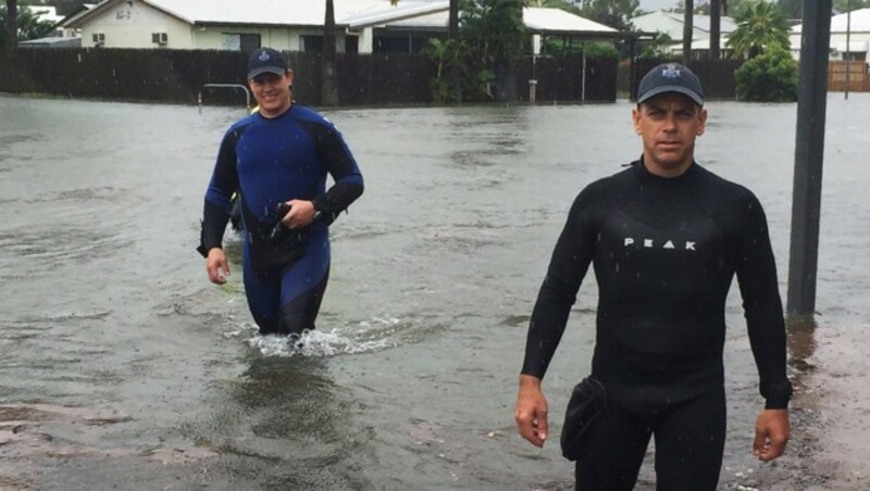 Zwei Polizisten waten in Townsville durchs Wasser. (Bild: AFP)