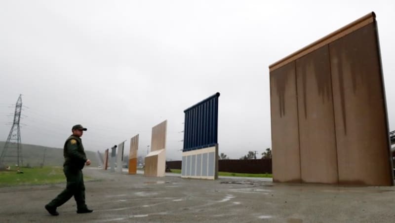 Ein US-Grenzpolizist vor mehreren Prototypen einer möglichen Grenzmauer, die wohl nicht mehr gebaut wird. (Bild: AP)