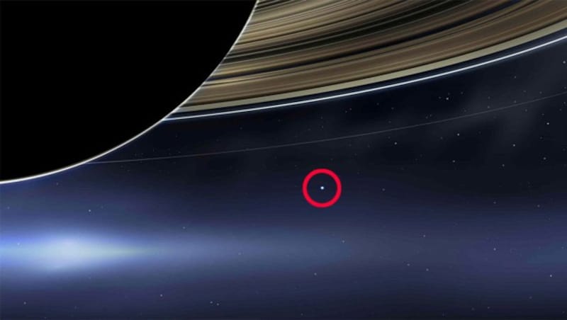 Die Saturnringe und die Erde (der rot markierte bläulich schimmernde Punkt) (Bild: NASA/JPL-Caltech, krone.at-Grafik)