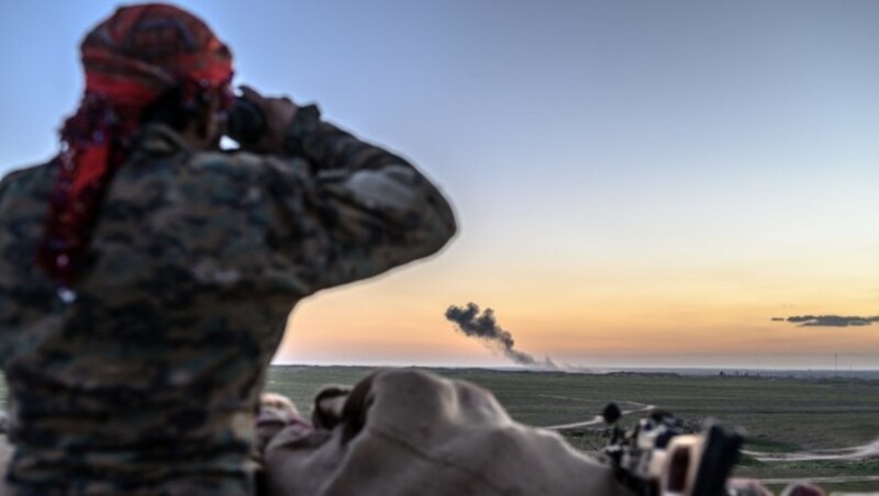 Ein Kämpfer der Syrischen Demokratischen Kräfte beobachtet Luftschläge auf die letzte IS-Bastion in Syrien aus der Ferne. (Bild: APA/AFP/Bulent KILIC)