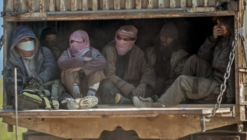 Mehrere als IS-Kämpfer identifizierte Männer werden in Lkws aus dem syrischen Dorf Baghouz befördert. (Bild: AFP )