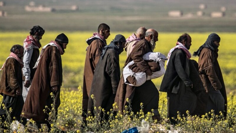 Eine Gruppe mutmaßlicher Dschihadisten verlässt Baghouz und begibt sich in die Hände der Syrischen Demokratischen Streitkräfte. (Bild: APA/AFP/Delil Souleiman)