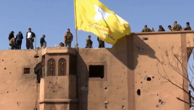 Soldaten der kurdisch-arabischen Allianz hissten auf einem Gebäude in Baghouz die SDF-Flagge. Sie zeigt: Das IS-Kalifat ist „vollständig eliminiert“. (Bild: ruptly.tv)