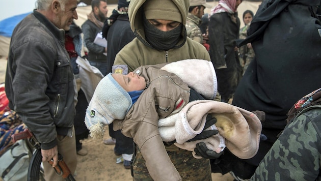 Eine kurdische Kämpferin hält ein aus der letzten IS-Hochburg Baghouz in Ostsyrien gerettetes Kleinkind in den Armen. (Bild: APA/AFP/FADEL SENNA)